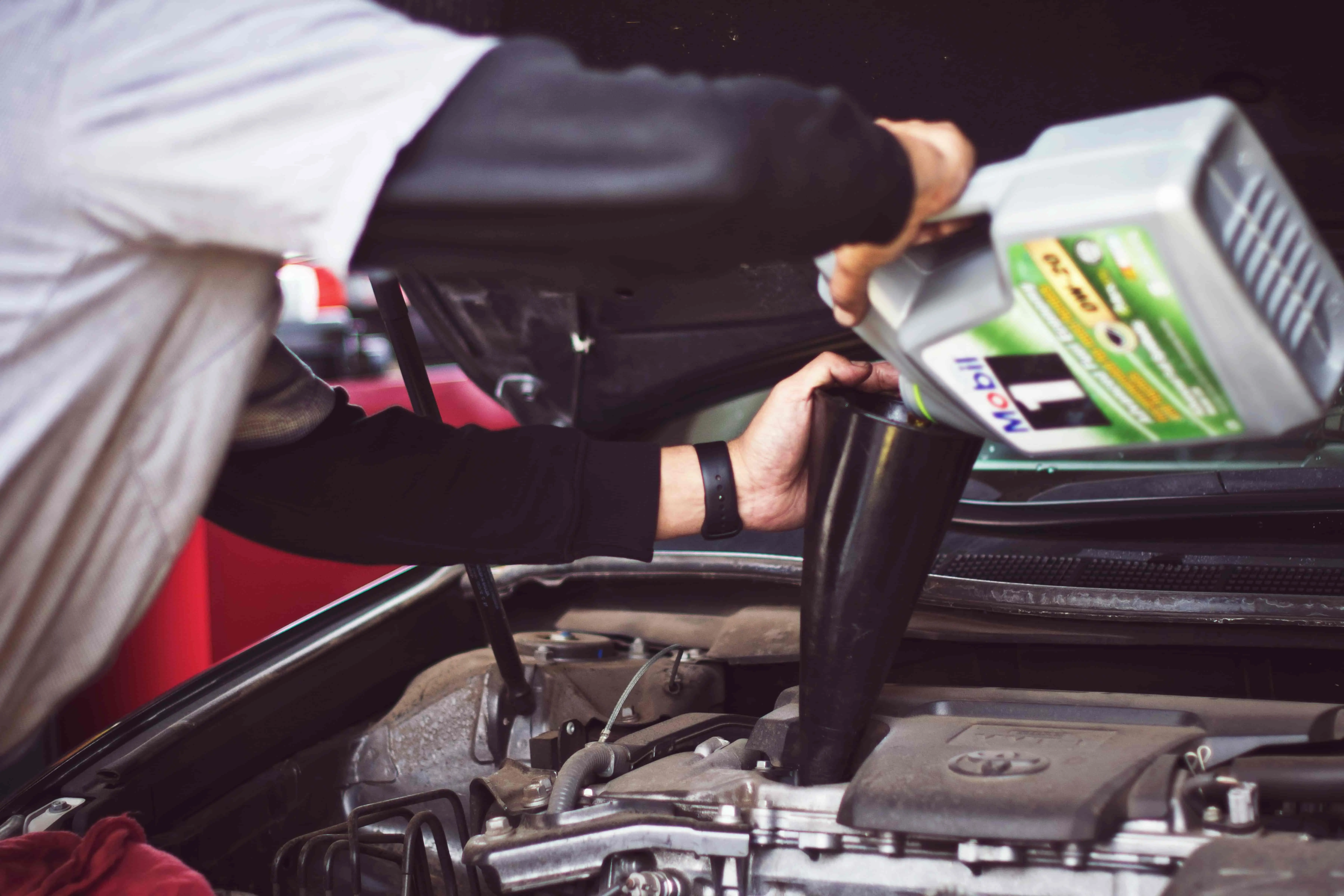 Foto de um homem inspecionando o motor de um carro